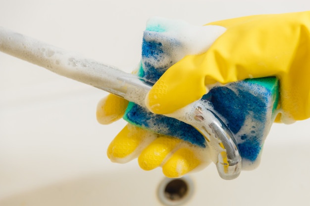 cleaning-bathroom-faucet-with-detergent-yellow-rubber-gloves-with-blue-sponge_95675-489